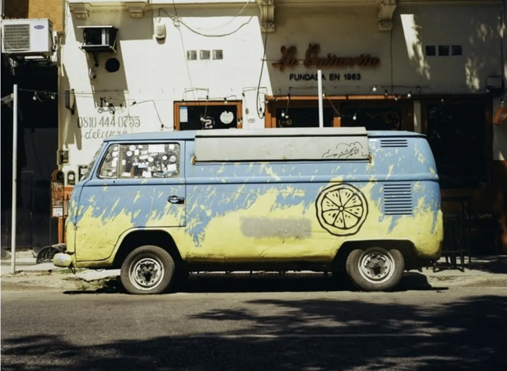 A sun-faded vintage camper van parked on a quiet street — life on the open road.